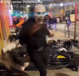 費城發生大規模搶劫事件，一名戴面具男子再搜刮商店財物後跑到街上。 圖 : 影片截圖