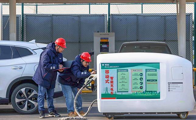 Technicians of the State Grid debug a charging robot for electric vehicles at a service area along the Beijing-Xizang Expressway on Jan. 23, 2025. (Xinhua/Li Xin)