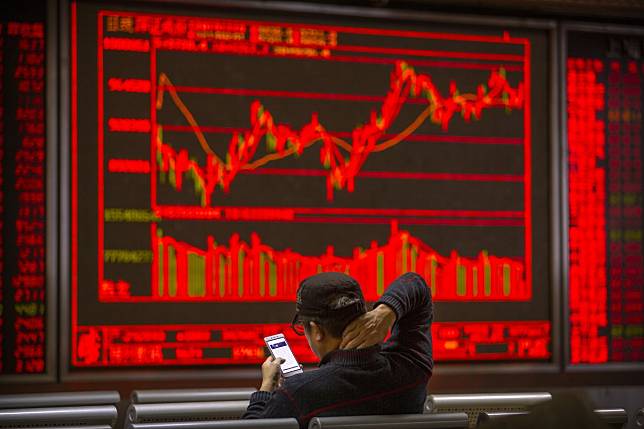 A Chinese investor uses his smartphone as he monitors stock prices at a brokerage house in Beijing on November 19, 2019. In mainland China, red signals gains. Photo: Associated Press