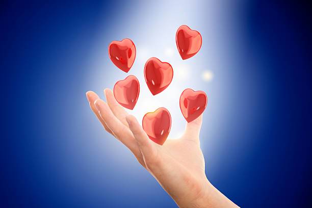 Hand holding hearts agains blue background