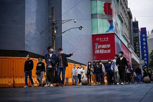 十一長假後上海疫情浮現，多區出現無症狀感染者足跡。圖為上海民眾逛街仍戴著口罩。（路透）