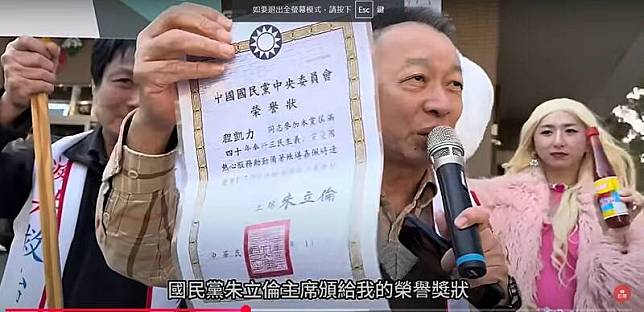 中華保台反共復國黨負責人程凱力等人到場，並秀出國民黨頒給的40年國民黨員獎狀。(擷取自八炯的影片)