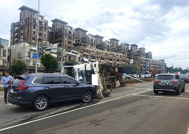 一輛大貨車昨日行駛沙鹿區向上路長下坡路段，疑煞車失靈連續撞擊四輛車後翻覆，造成三人受傷送醫。（記者陳金龍攝）