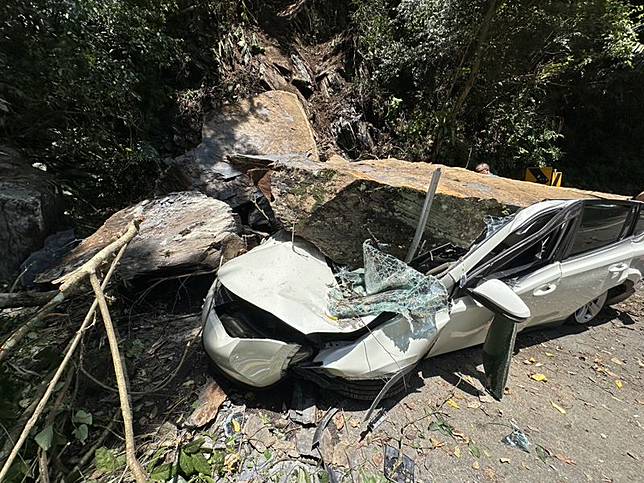 新北市烏來山區今日上午發生落石坍方，造成一部停放路旁的自小客車遭巨石砸中，所幸駕駛不在車上。（翻攝畫面）