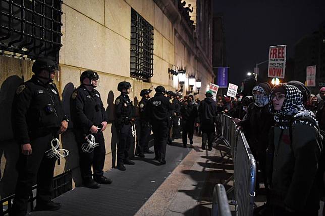 People participate in a pro-Palestinian demonstration as police officers stand guard outside Columbia University in New York, the United States, on April 24, 2024. (Xinhua/Li Rui)