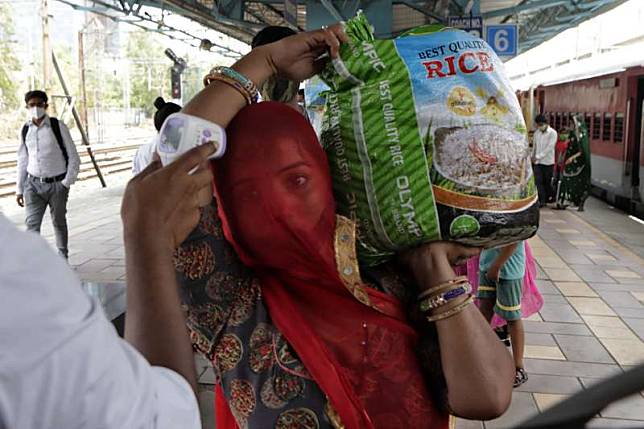 印度新冠疫情趨緩。孟買火車站的站務員為乘客量測體溫。（AP）