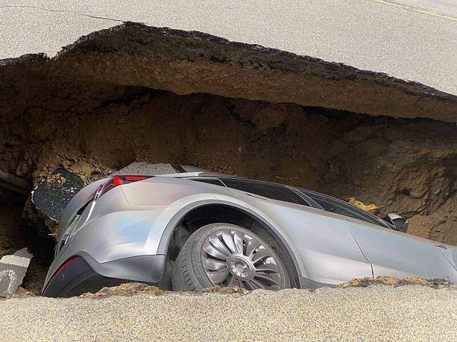 新竹縣竹北市莊敬六街路側停車格突然下陷，導致一輛車整個掉進洞裡。(圖由讀者提供)