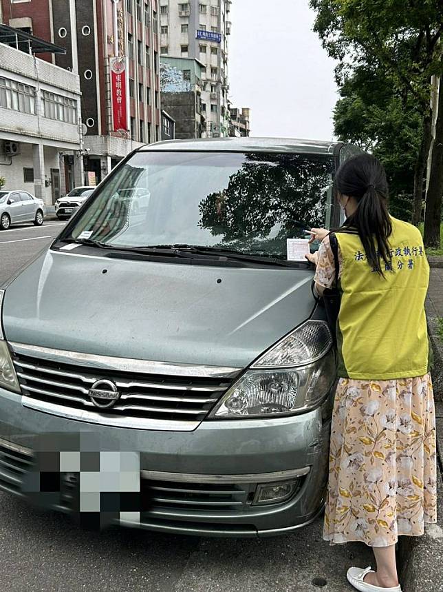 女子不繳通行費及罰鍰，車子停在信一路停車格，遭宜蘭分署人員執行查扣。（記者張上耕翻攝）