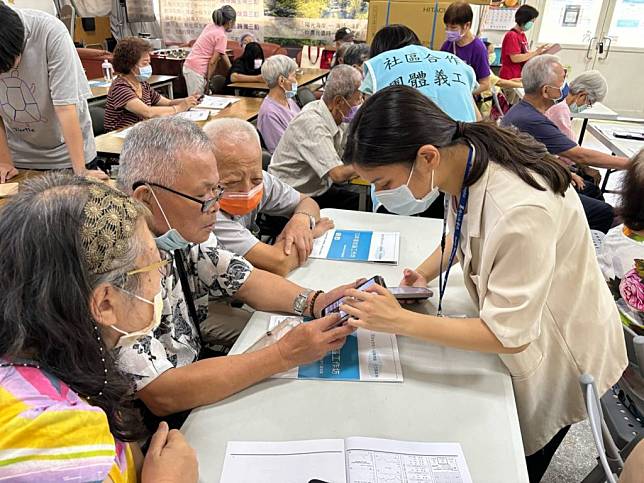 淡水馬偕杜宜靜管理師（右）教導長輩下載並使用「馬偕醫生到我家」APP。（新北市社會局提供）