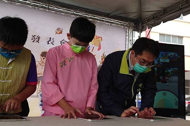 台南市政府文化局23日發表以藝陣文化「西港刈香」 為主題開發的音樂手機遊戲「咚隆咚隆跳陣頭」，台 南市長黃偉哲（右）並與學童們一起體驗試玩。 中央社記者楊思瑞攝 111年1月23日  
