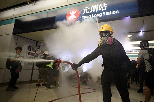A protester uses a fire hose as Yuen Long MTR station is vandalised. Photo: Winson Wong