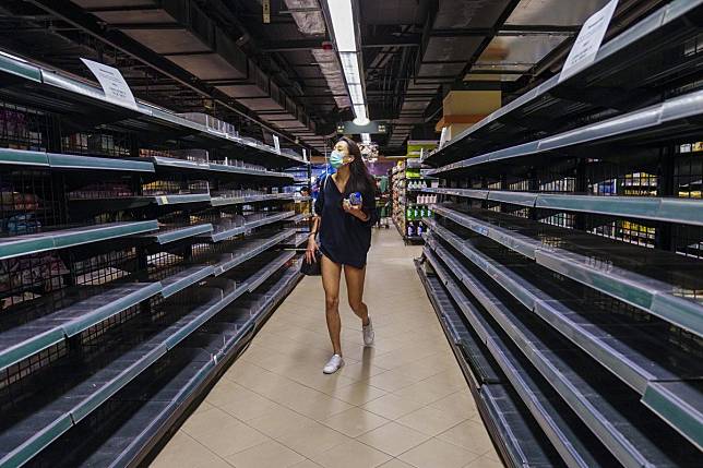 A customer wearing a face mask shops next to partially empty shelves of instant noodles. Photo: Sam Tsang
