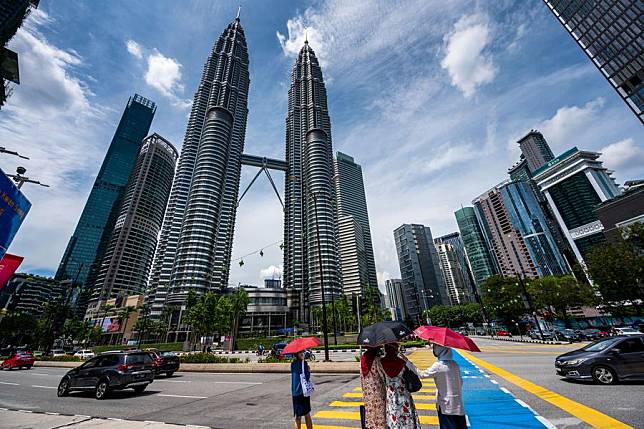 People wait for traffic lights in front of the Petronas Twin Towers in Kuala Lumpur, Malaysia, May 7, 2021. (Photo by Chong Voon Chung/Xinhua)