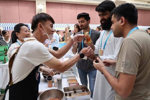 Participants taste suanye, a snack of pickled fruits and vegetables from the Guangxi Zhuang autonomous region, at a promotional event in Beijing on Friday. Wang Jing/China Daily