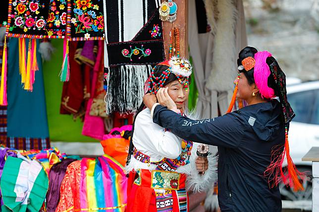 A tourist adjusts Tibetan attire before a photo session at a hamlet in Danba County, Tibetan Autonomous Prefecture of Garze, southwest China's Sichuan Province, March 23, 2024. (Xinhua/Shen Bohan)