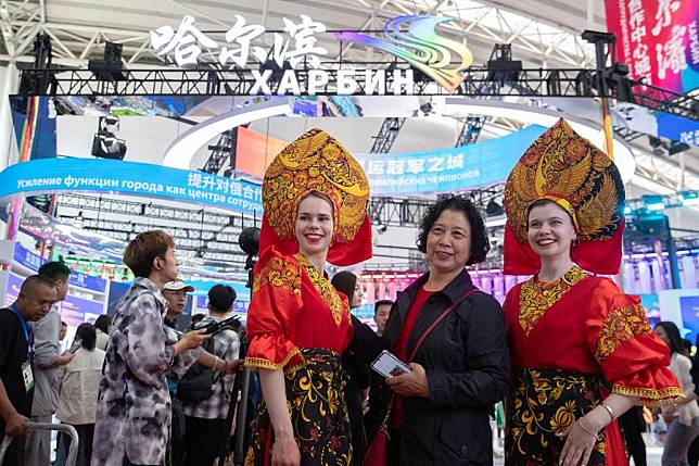 A participant poses for photos with Russian performers during the 8th China-Russia Expo in Harbin, northeast China's Heilongjiang Province, May 18, 2024. (Xinhua/Zhang Tao)