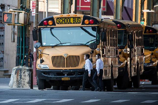 Children walk past school buses in the Borough Park neighborhood in the Brooklyn borough of New York, the United States, Oct. 4, 2020. (Photo by Michael Nagle/Xinhua)