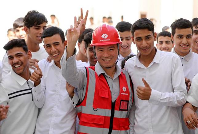 Students pose for a group photo with a Chinese engineer at the Al-Khudar High School constructed by the Power Construction Corporation of China (PowerChina) in Al-Muthanna Province, Iraq, on Oct. 8, 2024. (Xinhua/Khalil Dawood)