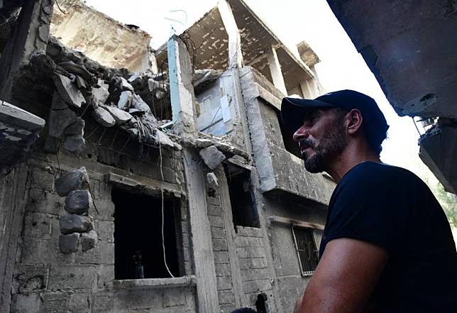 Mohammed Al-Aqad looks at his war-damaged apartment at the Yarmouk camp in Damascus, Syria, June 19, 2024. (Photo by Ammar Safarjalani/Xinhua)