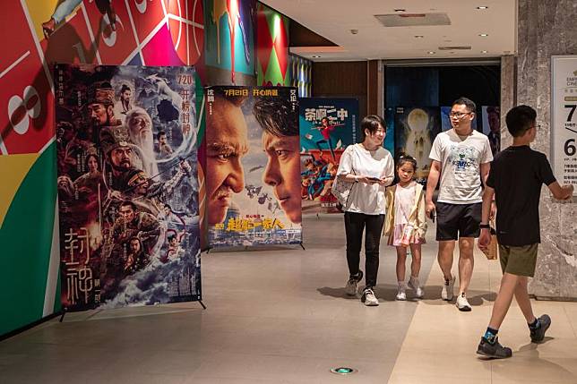 People walk past film posters outside a cinema in Yubei District of Chongqing, southwest China, July 30, 2023. (Xinhua/Chu Jiayin)