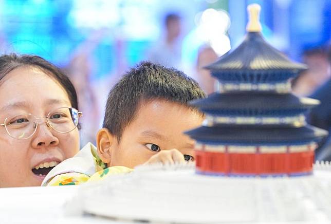 Visitors view a cultural creative product themed on the Hall of Prayer for Good Harvests, or Qiniandian, of the Tiantan (Temple of Heaven) Park, during the 2024 China International Fair for Trade in Services (CIFTIS) at the Shougang Park in Beijing, capital of China, Sept. 15, 2024. (Xinhua/Chen Yehua)