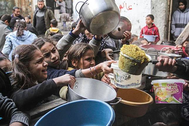 Palestinians receive free food from a food distribution center in Gaza City, on Dec. 27, 2024. (Photo by Mahmoud Zaki/Xinhua)