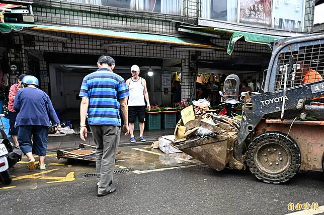 受到山陀兒颱風外圍環流影響，新北市金山區降下大雨，多處出現淹水情形。隔日雨勢減緩民眾開始清理遭水淹的家園及攤位。(記者陳志曲攝)