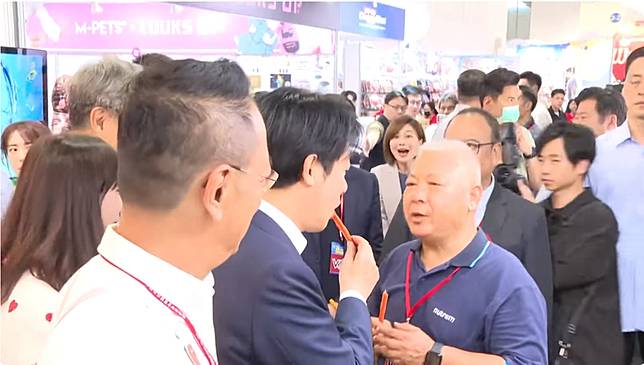總統賴清德今上午出席「2026展昭台北寵物用品展」開幕典禮，在逛到某處狗肉乾攤位時，更直接將狗肉乾拿起來試吃，讓一旁的隨扈、幕僚都十分驚訝，總統府發言人郭雅慧更被拍下驚訝張開嘴的畫面。(翻攝共訊)