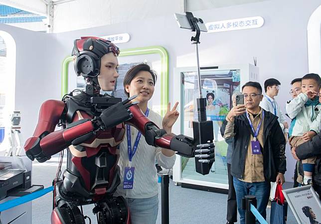 A humanoid robot takes selfies with a visitor at the 7th World Voice Expo in Hefei, east China's Anhui Province, Oct. 24, 2024. The 7th World Voice Expo and the iFlytek 1024 Global Developer Festival kicked off here on Thursday. The latest achievements and applications of AI technology will be on display at the four-day event. (Xinhua/Fu Tian)