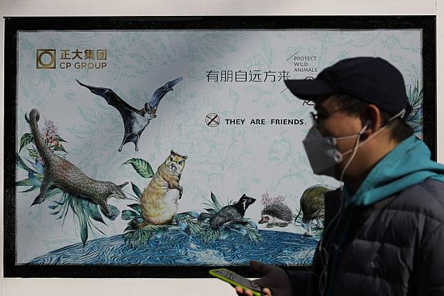 A man walks by a poster promoting the protection of wildlife animals in Beijing on March 11, 2020. Authorities have cracked down on the sale of wild animals for food. Photo: AP