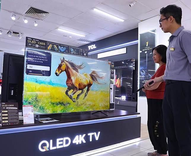 A salesperson introduces the performance of TCL TV sets to a customer at a store in Hanoi, Vietnam, Oct. 11, 2024. (Xinhua/Yao Qilin)