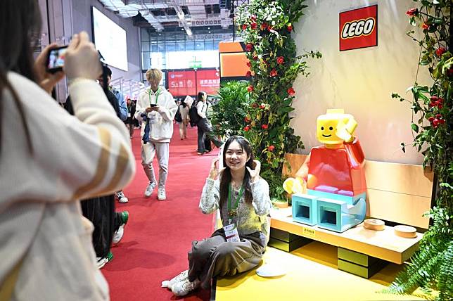 A visitor poses for photos at the booth of LEGO Group, a full-time attender of the China International Import Expo (CIIE), during the 7th CIIE in east China's Shanghai, Nov. 9, 2024. (Photo by Chen Haoming/Xinhua)