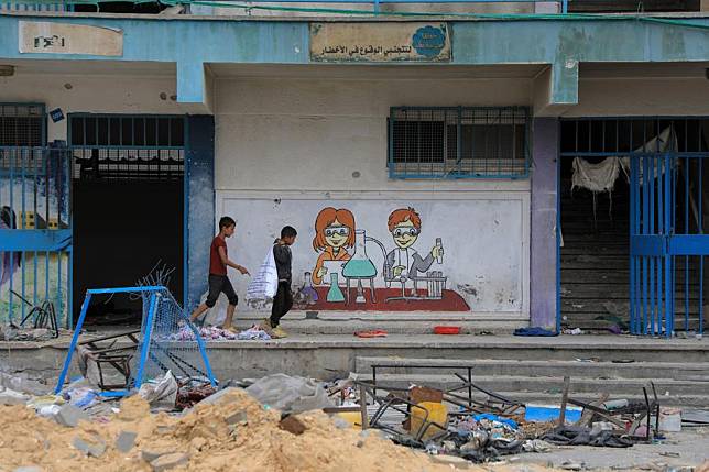 Children walk past a school building affiliated with the United Nations Relief and Works Agency for Palestine Refugees in the Near East (UNRWA) in the southern Gaza Strip city of Khan Younis, May 2, 2024. (Photo by Rizek Abdeljawad/Xinhua)