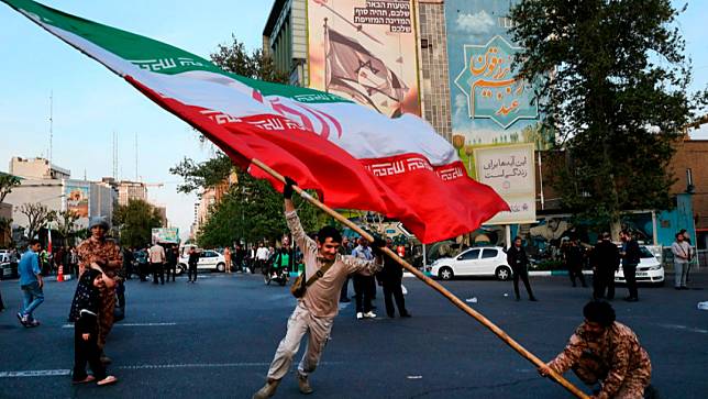 伊朗德黑蘭街頭有民眾揮舞巨大伊朗國旗，慶祝空襲以色列行動。美聯社