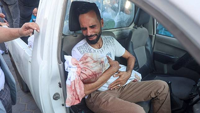 2023年10月31日，加薩中部的舒哈達阿克薩醫院（Shuhada Al-Aqsa hospital）外，一名男子抱著自己死於空襲的兒子艾哈邁德（Ahmed al-Badrasawi）。路透社