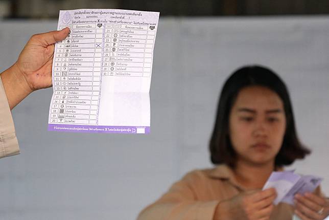 Electoral staff members show a ballot during vote counting at the general election in Mae Hong Son