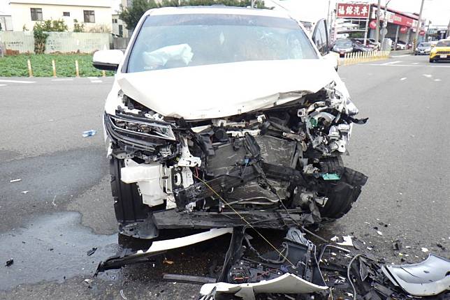 林男無照酒駕闖紅燈，與直行的遊覽車發生碰撞，轎車車頭嚴重毀損。（記者陳金龍翻攝）