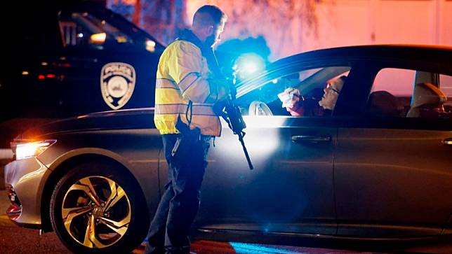 美國新罕布夏州11月17日發生槍擊案，造成1人死亡，案發後警方在現場戒備，圖為警察確認駕車出入案發醫院的員工身分。美聯社