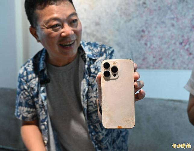 手機主人陳志東拿著被龍膽石斑吞下的iPhone 16 。(記者李惠洲攝)