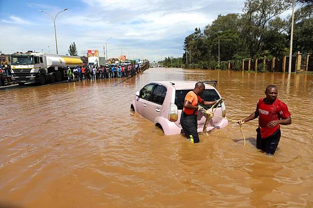 People pull a car submerged in flood water in Nairobi, capital of Kenya, on May 1, 2024. (Photo by Joy Nabukewa/Xinhua)