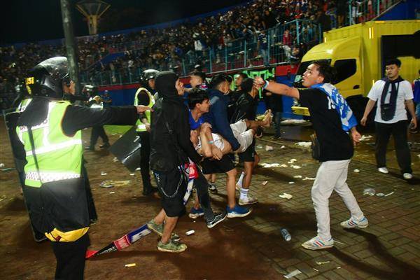 印尼1名足球迷2日被警方催淚彈擊中後，被其他人抬離現場。路透社
