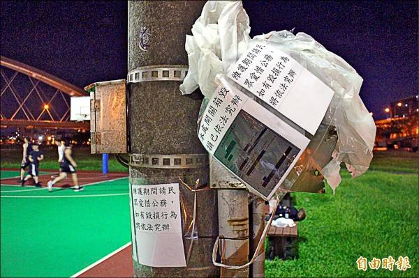 彩虹河濱公園籃球場照明燈電箱毀損、遭竊電，公園路燈管理處貼上地檢署傳票警告民眾。(記者黃捷攝)