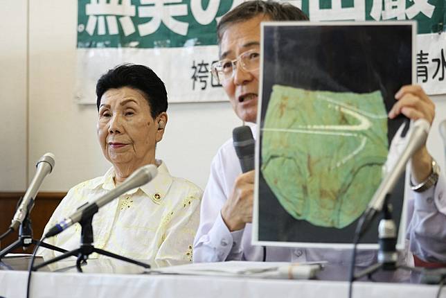 辯方在記者會上拿著檢方當年提交的「血衣物證照」。圖片來源：讀賣新聞 / AP / 達志影像  
