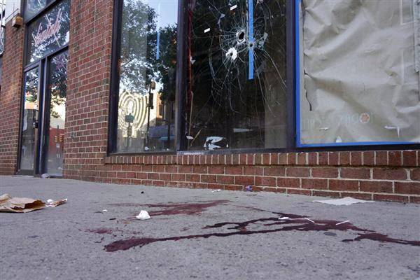 費城4日深夜發生街頭大規模槍擊案，店家窗戶留下彈孔，街道留下血跡。（圖片來源／美聯社）