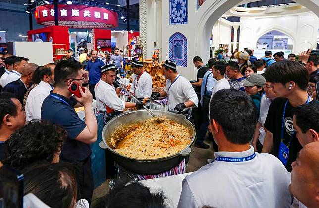 Staff members prepare specialty food at the booth of Uzbekistan during the 8th China-Eurasia Expo in Urumqi, northwest China's Xinjiang Uygur Autonomous Region, June 27, 2024. (Xinhua/Chen Shuo)