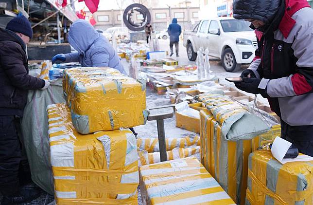 A courier ® collects packed frozen fish at Dongji fish market in Fuyuan, northeast China's Heilongjiang Province, Jan. 31, 2024. (Xinhua/Wang Jianwei)