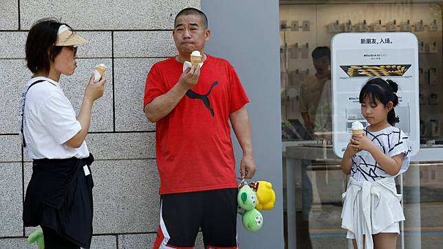 中國北京，23日民眾在熱浪紅色警報中吃冰淇淋。路透社