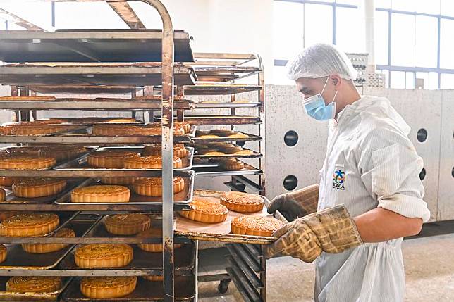 A baker arranges freshly baked mooncakes at a workshop in Hepu County, south China's Guangxi Zhuang Autonomous Region, Sept. 11, 2024. (Xinhua/Lin Qibo)