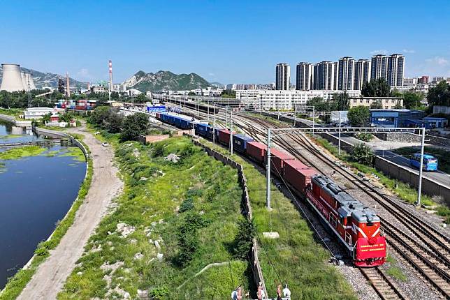 This aerial photo shows a freight train loaded with auto parts, home appliances and textile products pulling out of the Xiahuayuan railway cargo terminal in Zhangjiakou, north China's Hebei Province. (Photo by Wu Diansen/Xinhua)