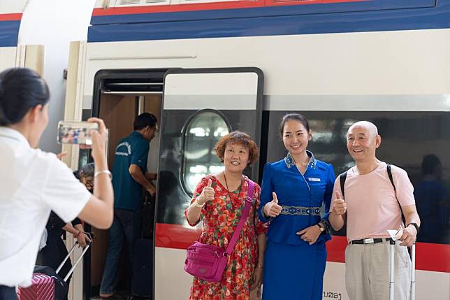 Passengers pose for a photo with a train of the China-Laos Railway at the Vientiane Station in Vientiane, Laos, Dec. 2, 2024. (Photo by Kaikeo Saiyasane/Xinhua)